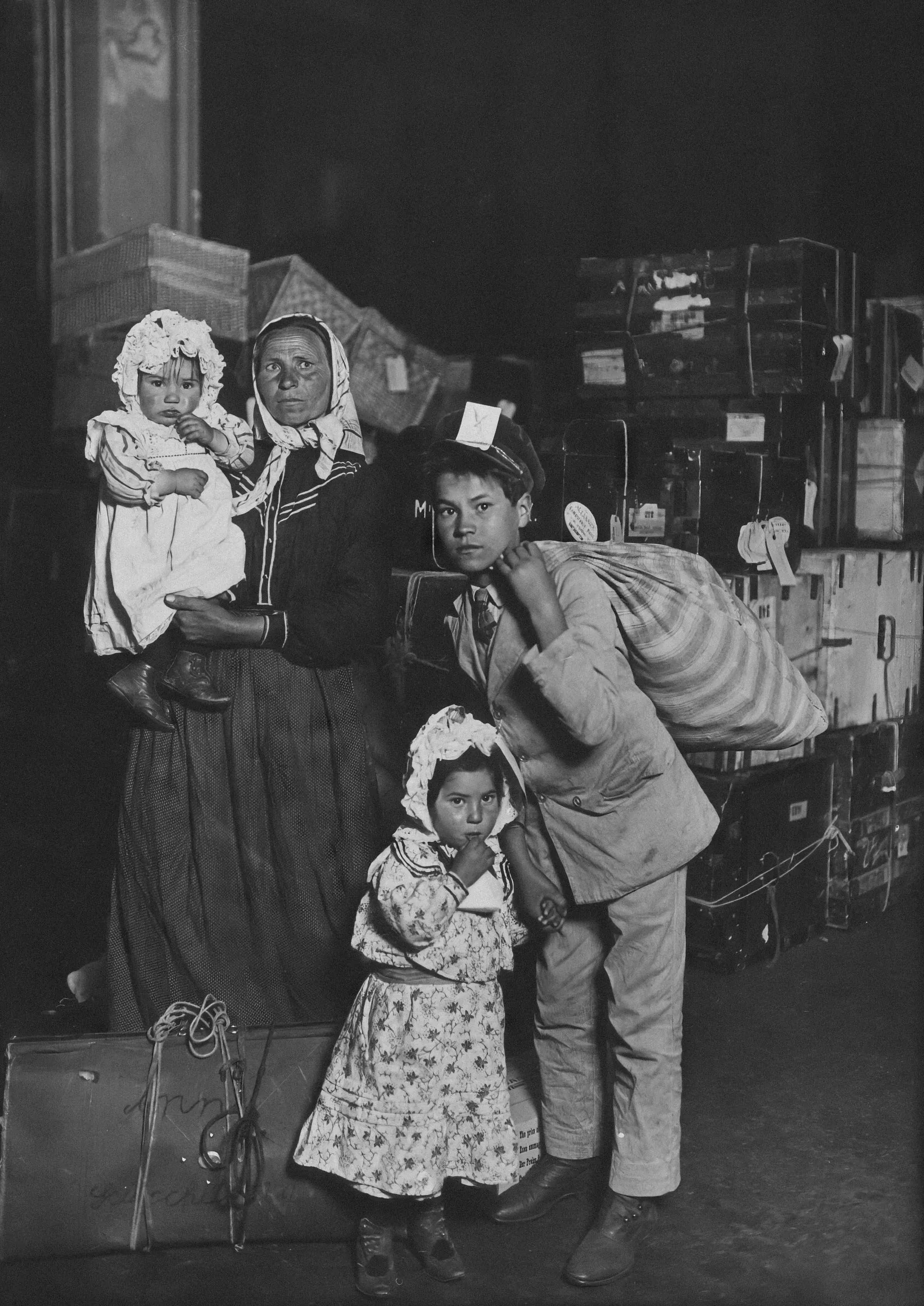 Italian mother and children standing among luggage in the Ellis Island baggage room in 1905.