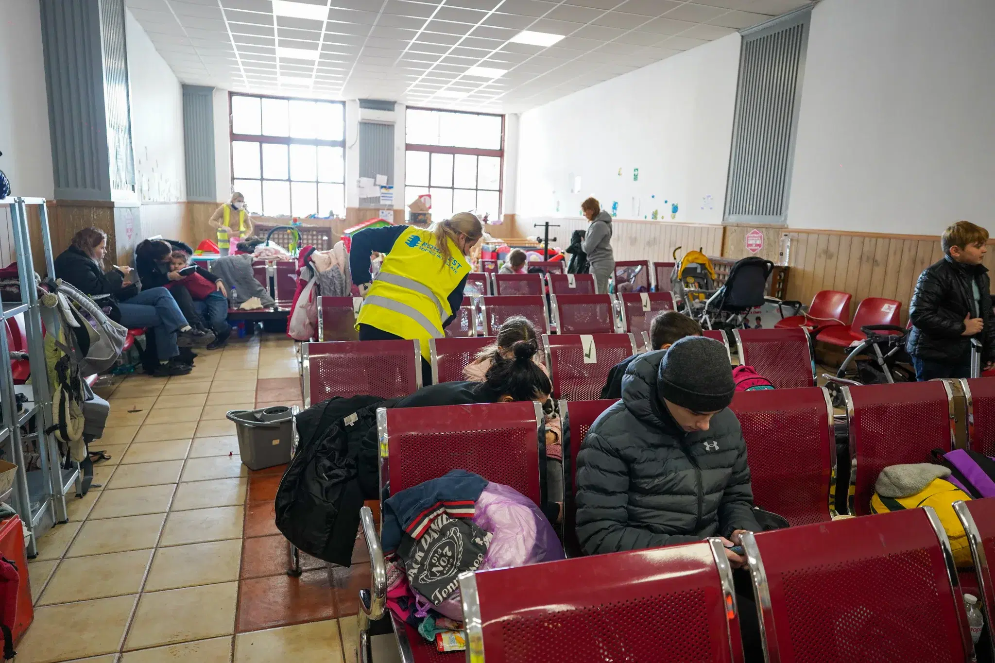 Ukrainian refugees resting on rows of seats inside a Romanian train station in 2022.