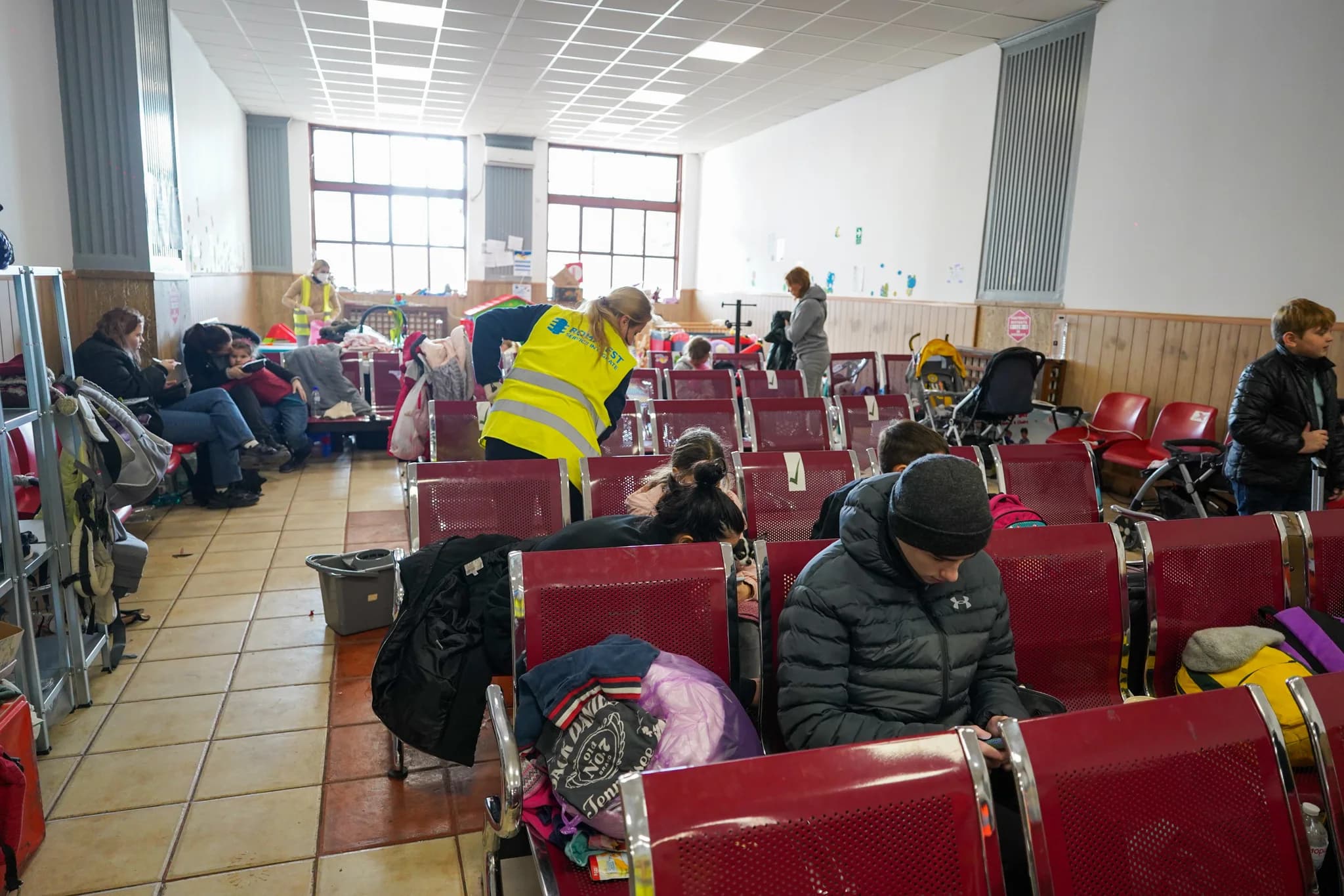 Ukrainian refugees resting on rows of seats inside a Romanian train station in 2022.